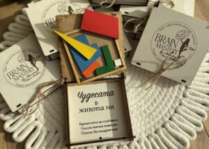 Отворена кутия на пъзела "Чудесата в живота ни" с цветните парчета на пъзела, всяко в различна форма, заобиколени от още кутии от пъзела